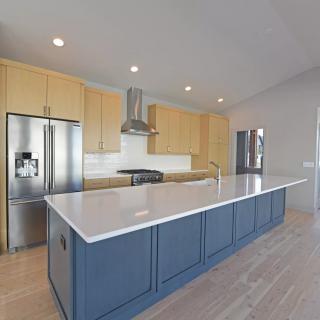 A modern kitchen featuring yellow cabinets and a blue island, equipped with stainless steel appliances.