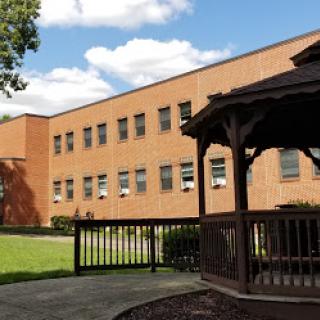 A serene view of a brick building alongside a gazebo, set against a clear blue sky.