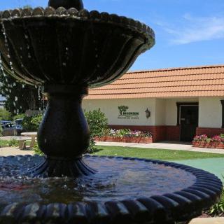 A scenic view of a fountain in the foreground with a building in the background on a sunny day.
