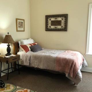 A cozy bedroom with a neatly made bed, bedside lamp, and decorative artwork on the walls.