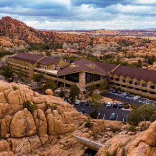 A hotel nestled among dramatic rock formations in a desert landscape under a cloudy sky.