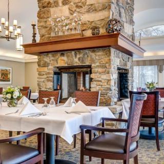 A cozy restaurant dining area featuring neatly set tables and a central stone fireplace.