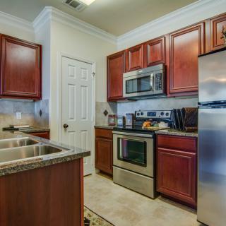 A modern kitchen with stainless steel appliances and wooden cabinets.