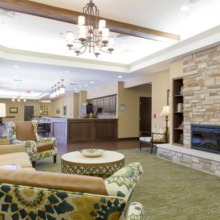 A spacious and well-lit lobby area with comfortable seating, a fireplace, and a chandelier, providing a welcoming atmosphere.