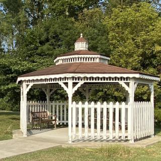 A charming white gazebo surrounded by greenery in a serene park setting.