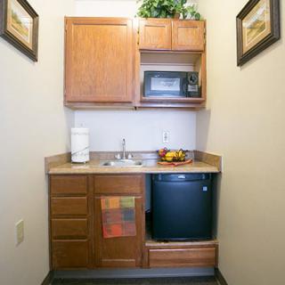A small kitchenette with a microwave, cabinets, and a sink.