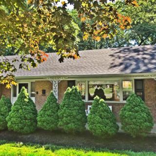 A suburban brick house surrounded by greenery and trees.