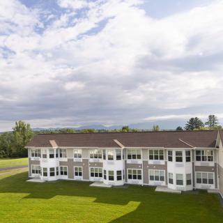 A large residential building with a well-maintained lawn under a cloudy sky.