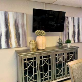 A modern living room setup featuring a stylish console, wall-mounted TV, and elegant artwork.