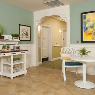 A cozy interior with a small round table, colorful artwork on the wall, and decorative plants.