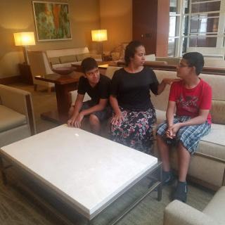 A mother engages in conversation with her two children in a cozy lounge setting.