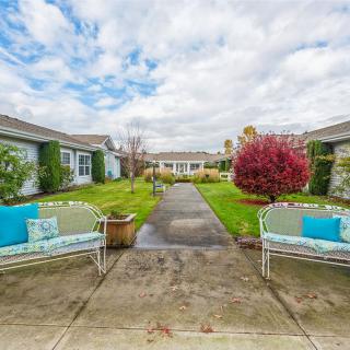 A serene courtyard with two benches and a lush garden path under a cloudy sky.
