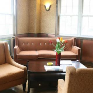 A cozy living room with a vintage sofa, armchairs, and a coffee table adorned with a vase of flowers.