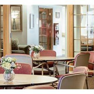 A cozy seating area featuring tables and chairs, adorned with fresh flowers, inviting a sense of relaxation.