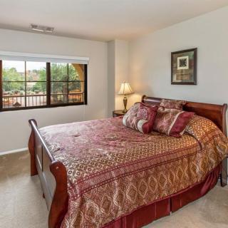 A cozy bedroom with a large bed, decorative pillows, and a bedside lamp near a window.