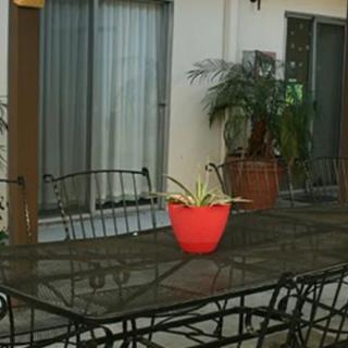 A patio area with metal furniture and a vibrant red planter on the table.