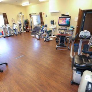 A spacious physical therapy room equipped with various exercise machines and rehabilitation tools.