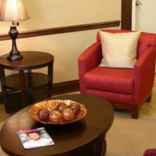 A cozy living room setup with a red armchair, side table with a lamp, and a coffee table with decorative items.