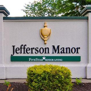 A sign for Jefferson Manor, a Five Star Senior Living community, surrounded by greenery.