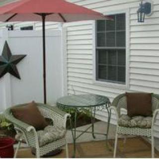 A cozy outdoor patio setup with wicker chairs, a glass table, and an umbrella.