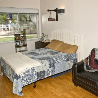 A cozy bedroom featuring a neatly made bed, a comfortable sofa, and natural light streaming through the window.