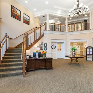 A spacious and elegant lobby with a chandelier, staircase, and stylish decor.