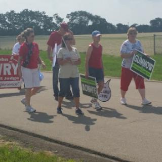 A group of protesters marching with signs on a sunny day.