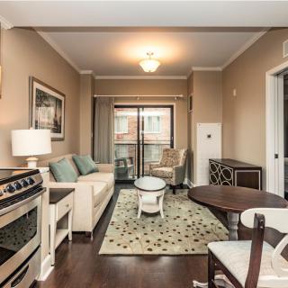 A cozy living room with a neutral color scheme, featuring a sofa, table, and decorative rug.