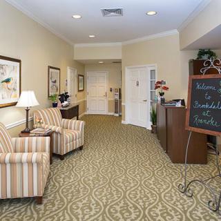 A cozy and well-furnished lobby area with two chairs, a lamp, and a decorative board.