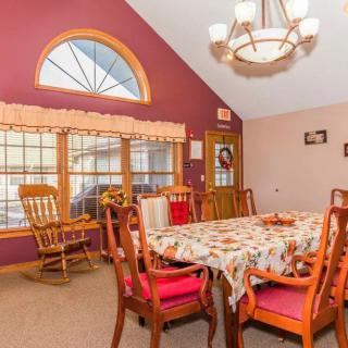 A cozy dining room with a large table and elegant chairs, featuring a chandelier and a window with a view.