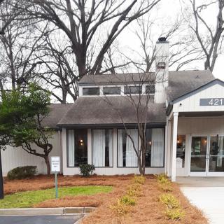 A quaint house surrounded by trees with a visible chimney and landscaped yard.