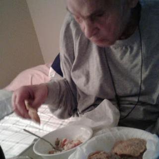 An elderly person enjoying a meal in a cozy indoor setting.