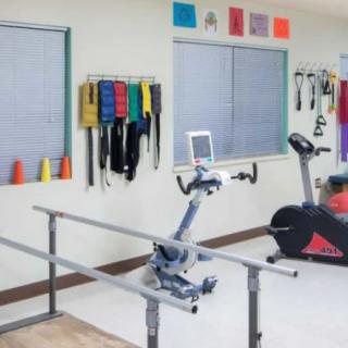 A physical therapy room equipped with exercise machines, resistance bands, and various rehabilitation tools.