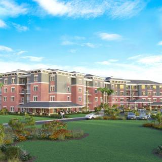 A modern residential apartment complex with landscaped surroundings under a clear blue sky.