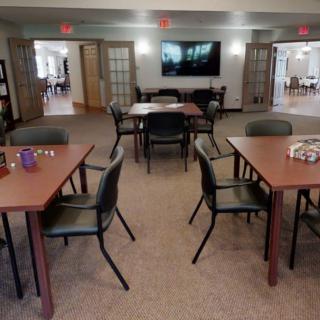A communal room with tables, chairs, and a television, designed for gatherings or activities.