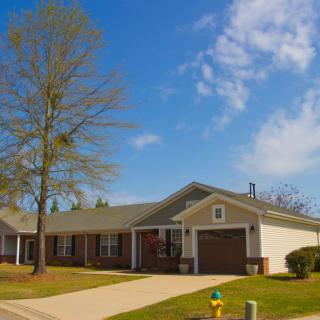 A suburban house with a driveway and garage under a partly cloudy sky.