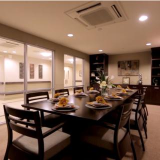 A modern dining room with a large table set for dinner, featuring warm lighting and elegant decor.