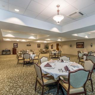 A spacious dining room set up for a formal event with elegantly arranged tables and chairs.