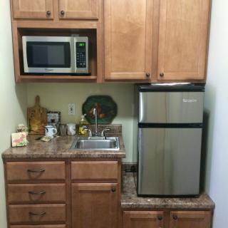 A compact kitchenette with a microwave, mini fridge, and sink.