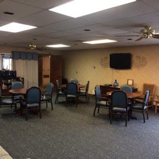A dining area with several tables and chairs, a television on the wall, and decorative items.