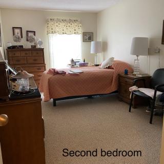 A cozy second bedroom with a neatly made bed and wooden furniture.