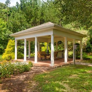 A charming white gazebo surrounded by lush greenery in a tranquil garden setting.
