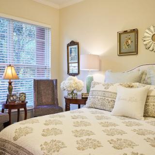 A cozy bedroom with elegant decor, featuring a bed with patterned bedding and soft lighting from lamps.