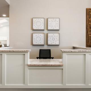A modern reception desk with artwork on the wall and a computer on the counter.
