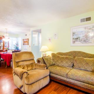 Cozy living room with a sofa and recliner, featuring wood flooring and wall art.