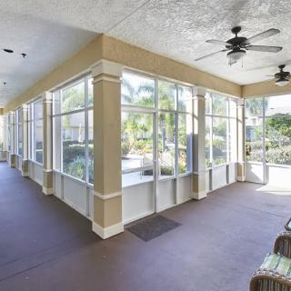 A bright and airy sunroom with large windows, ceiling fans, and patio furniture.