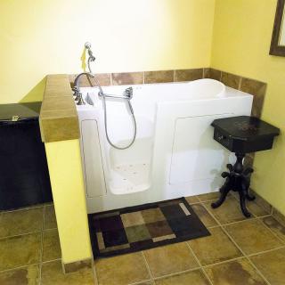 A bathroom featuring a walk-in bathtub with tiled surroundings.