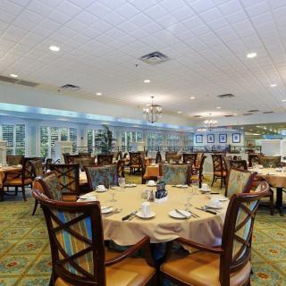 A spacious and elegantly arranged dining room with round tables set for a meal.