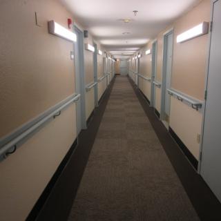 A long, empty hallway with doors on either side and fluorescent lighting overhead.