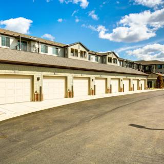 A row of residential townhouses with individual garages and a clear blue sky.